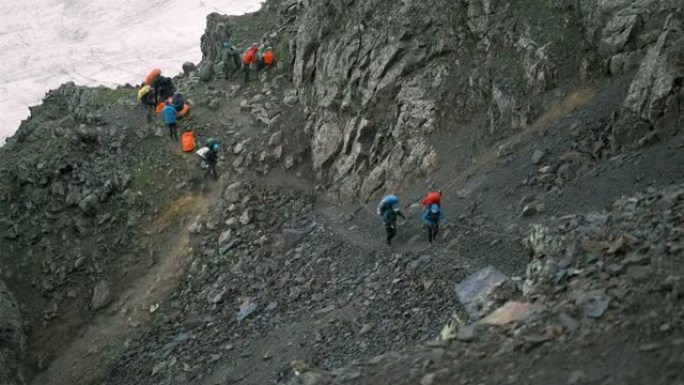 登山者轮流在山上紧紧抓住绳子行走。