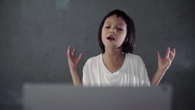 小女孩看着笔记本电脑，在客厅唱歌。