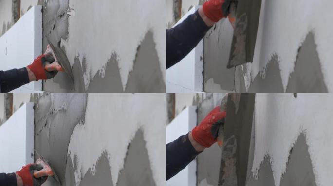 建筑工人用粘性水泥胶覆盖房屋墙壁，安装聚苯乙烯泡沫塑料隔热板进行隔热保护。