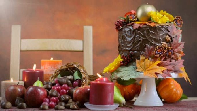 美丽的感恩节秋季餐桌设置与秋季主题巧克力蛋糕，聚宝盆和蜡烛。