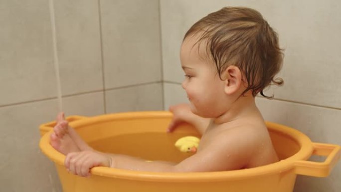 可爱的女婴坐在浴缸里微笑的慢动作视频。