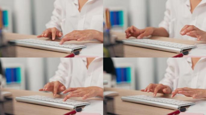 站在木桌上的电脑上的键盘特写镜头，穿着白衬衫的女工，年轻的手，在键盘上打字，在按键上敲击手指