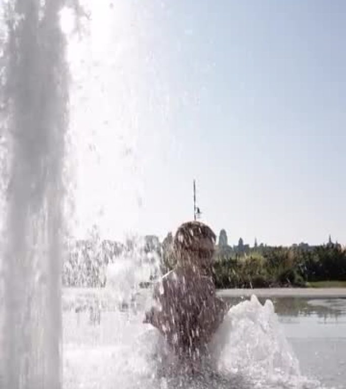 可爱的红发男孩在喷泉里玩耍