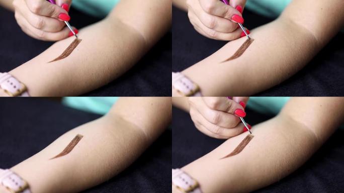 女孩用指甲花在她的手上画眉毛。