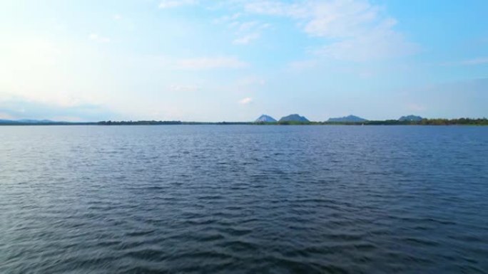 4k鸟瞰图无人机飞越泰国乡村的水库。蓝天有云和太阳，日出时的云。