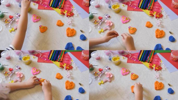 小女孩的手用五颜六色的粘土面团做花和太阳等，