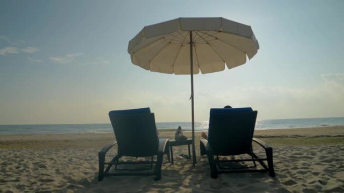在泰国华欣的白色沙滩上，孩子们一起坐在沙滩椅上，遮阳伞。度假概念。