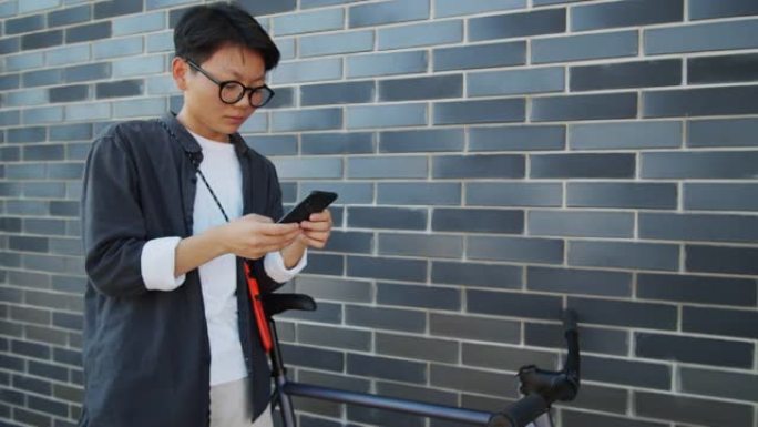 亚洲妇女站在街上骑自行车并使用智能手机