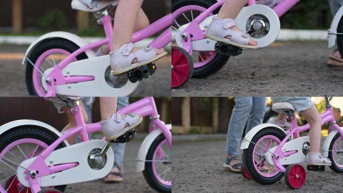 一个小女孩在乡村道路上踩踏板并骑粉红色的自行车。