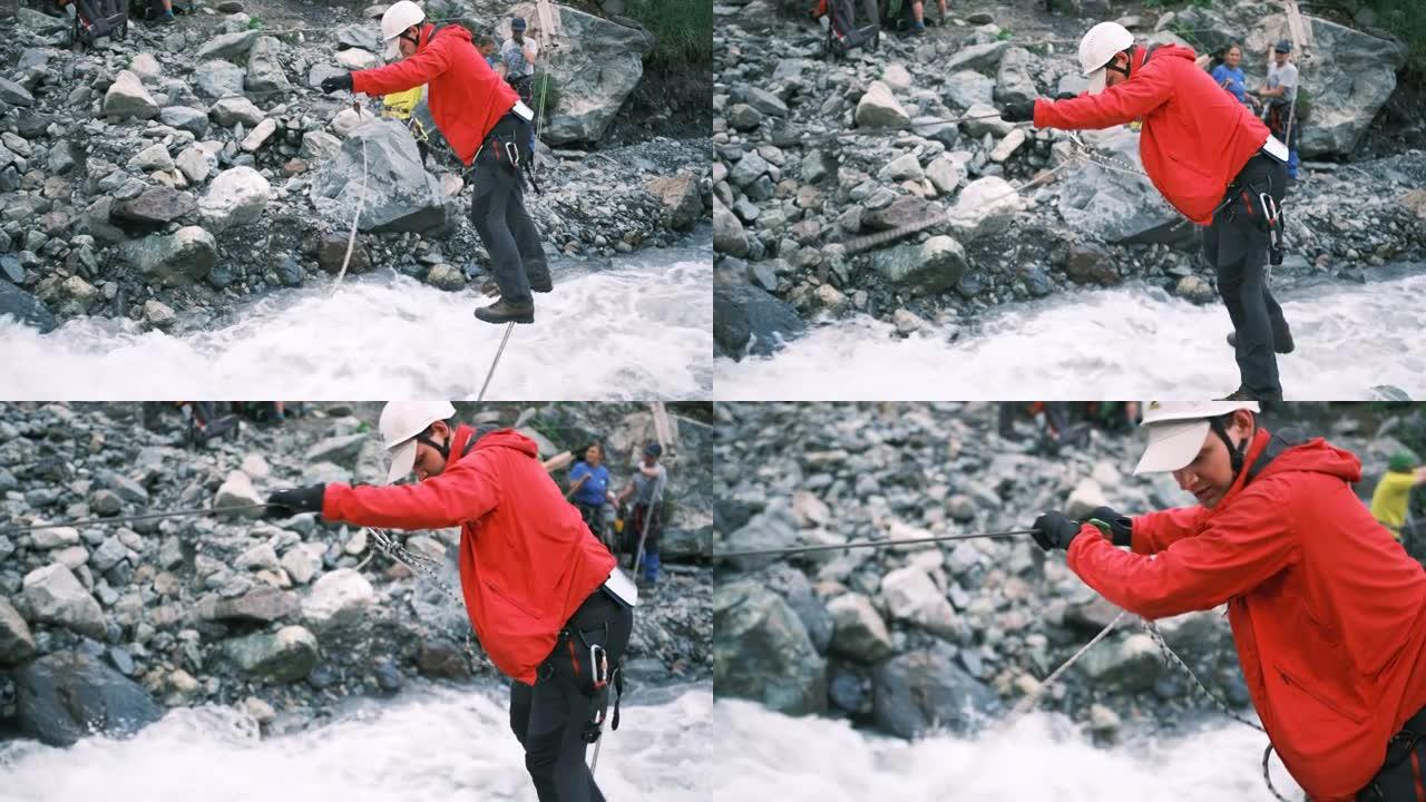 一名游客使用用登山扣固定的垂直绳索过河。侧视图