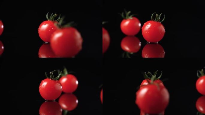 成熟的红色西红柿，带有绿色的水滴尾巴，以慢动作在厨房桌子的黑色反光表面上旋转。潮湿闪亮的夏季蔬菜在黑