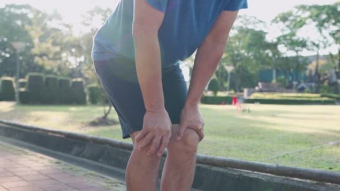 近距离拍摄亚洲男子在公园做膝盖热身，关节韧带骨问题，踝关节扭伤运动损伤预防，健康积极的生活方式，跑步