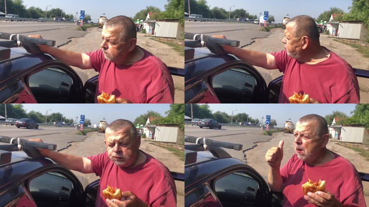 饥饿的高加索高级司机在Ukraian路上站在他的汽车附近吃patty