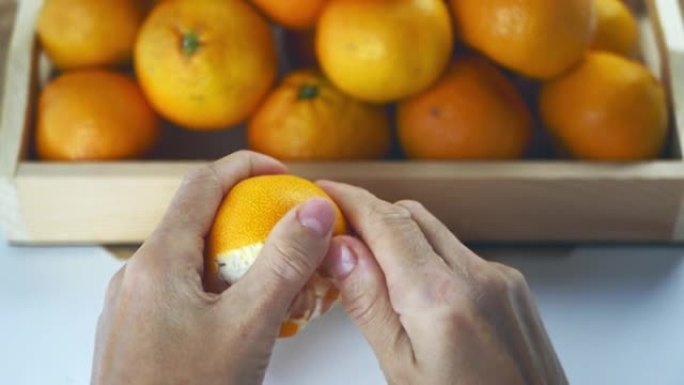 女性的手在盒子上剥橘子。在市场特写镜头的木箱中新鲜收获橘子