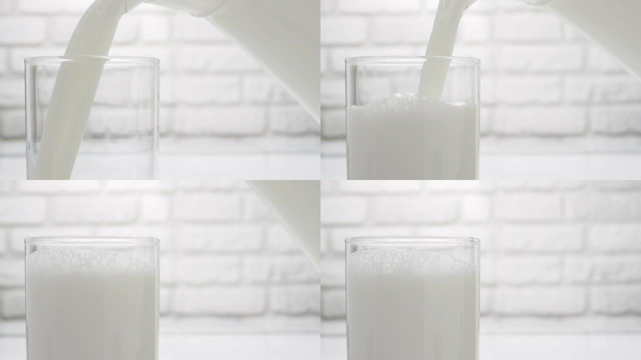 在白色砖墙的背景下，从水罐中倒入牛奶。乳制品特写。牛奶流入玻璃杯