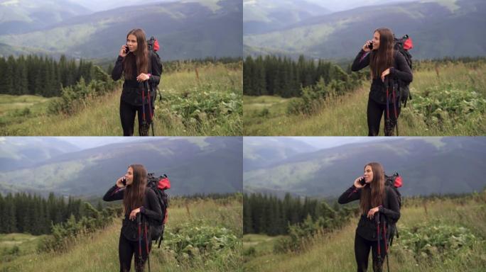 年轻美丽的高加索女人徒步旅行者站在山顶上，在她的智能手机上与亲人交流。