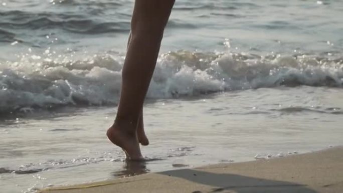 年轻的女孩在海边tip起脚尖，在汹涌的海浪中反射着阳光。假期和幸福概念。慢动作