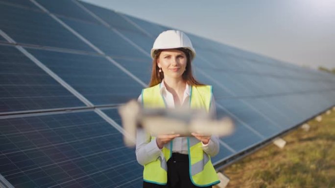 一位女工程师在太阳能发电厂的背景下操作无人机的肖像。太阳能电池板阵列安装。技术和生态。日落