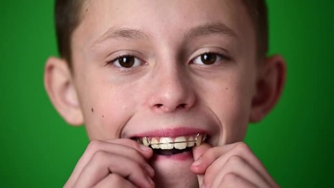 孩子放在牙板上，以对齐弯曲的牙齿，绿色背景上的孩子肖像。