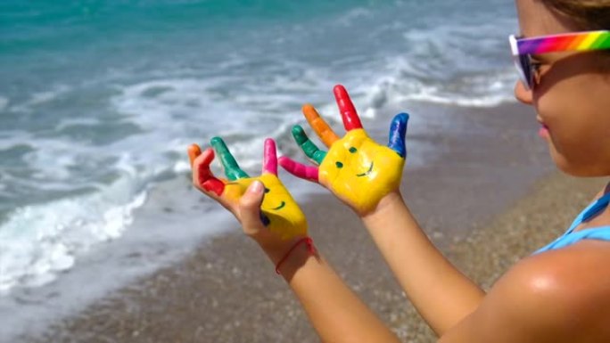 一个孩子在海上，手上画着颜料，微笑着。选择性聚焦。自然。