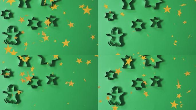 圣诞明星的动画落在绿色背景上的饼干模具上