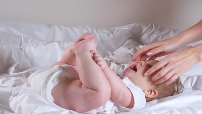 女人的手挠痒痒可爱的7个月女婴躺在床上