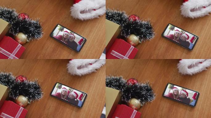 微笑的高加索父亲和女儿戴着圣诞老人的帽子在智能手机上的圣诞节视频通话中