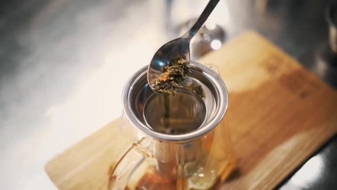 茶饮料。准备茶。特写。顶视图。将一勺干燥的，花的，多叶的绿茶倒入茶壶中。果味浆果热饮