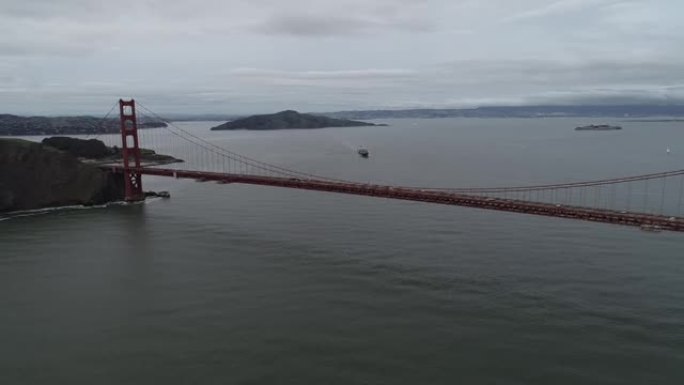 加利福尼亚州旧金山的金门大桥。多云的天空。恶魔岛和监狱，背景是集装箱船。美国