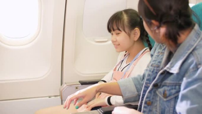 母亲在飞机上为女儿系安全带，旅行和度假概念