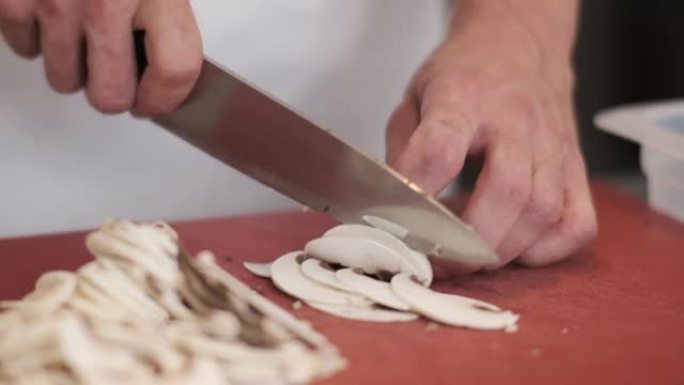 厨师在砧板上切碎蘑菇