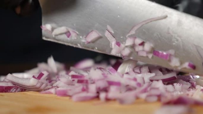 厨师用锋利的刀切新鲜的生洋葱。慢动作。在餐厅或家庭厨房做饭，做蔬菜餐，切蔬菜。在砧板上切碎洋葱。全高