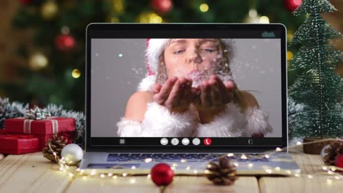穿着圣诞老人服装的快乐白人妇女在笔记本电脑上进行视频通话，带有圣诞节装饰和树木