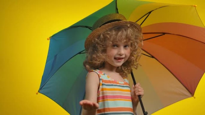 戴着彩虹伞的可爱的卷发金发女孩正在检查雨水