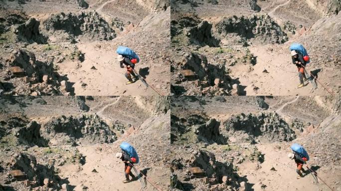一名游客抓住绳子，克服了山区的一个困难部分。