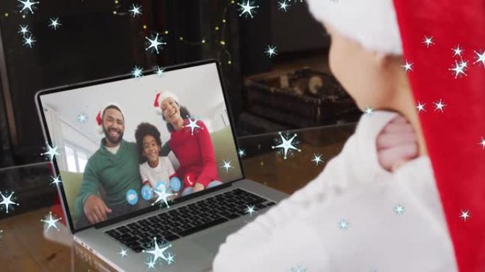 在与家人的笔记本电脑视频通话中，圣诞老人帽子中的白人女孩的圣诞明星动画
