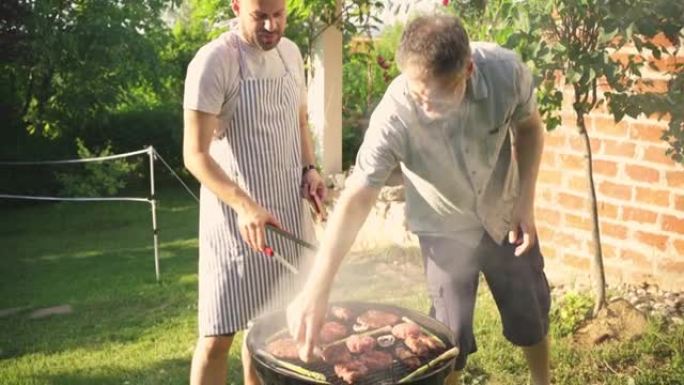 成年男性朋友，在花园里的BBG烤架上烧烤牛肉，芦笋和蘑菇