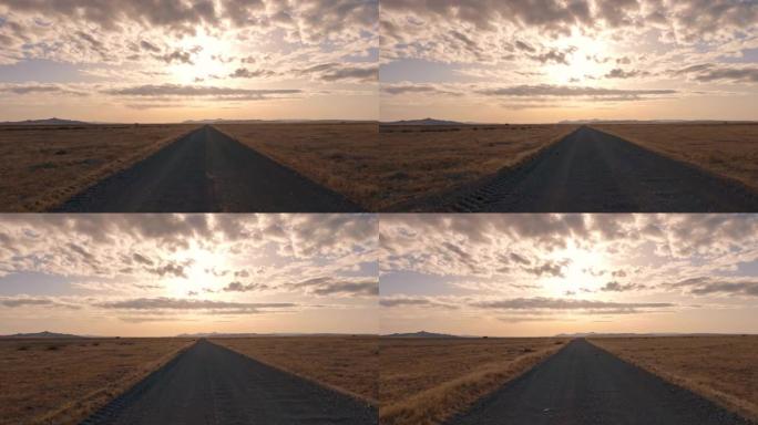 在平坦的犹他州沙漠上的土路上驶向太阳
