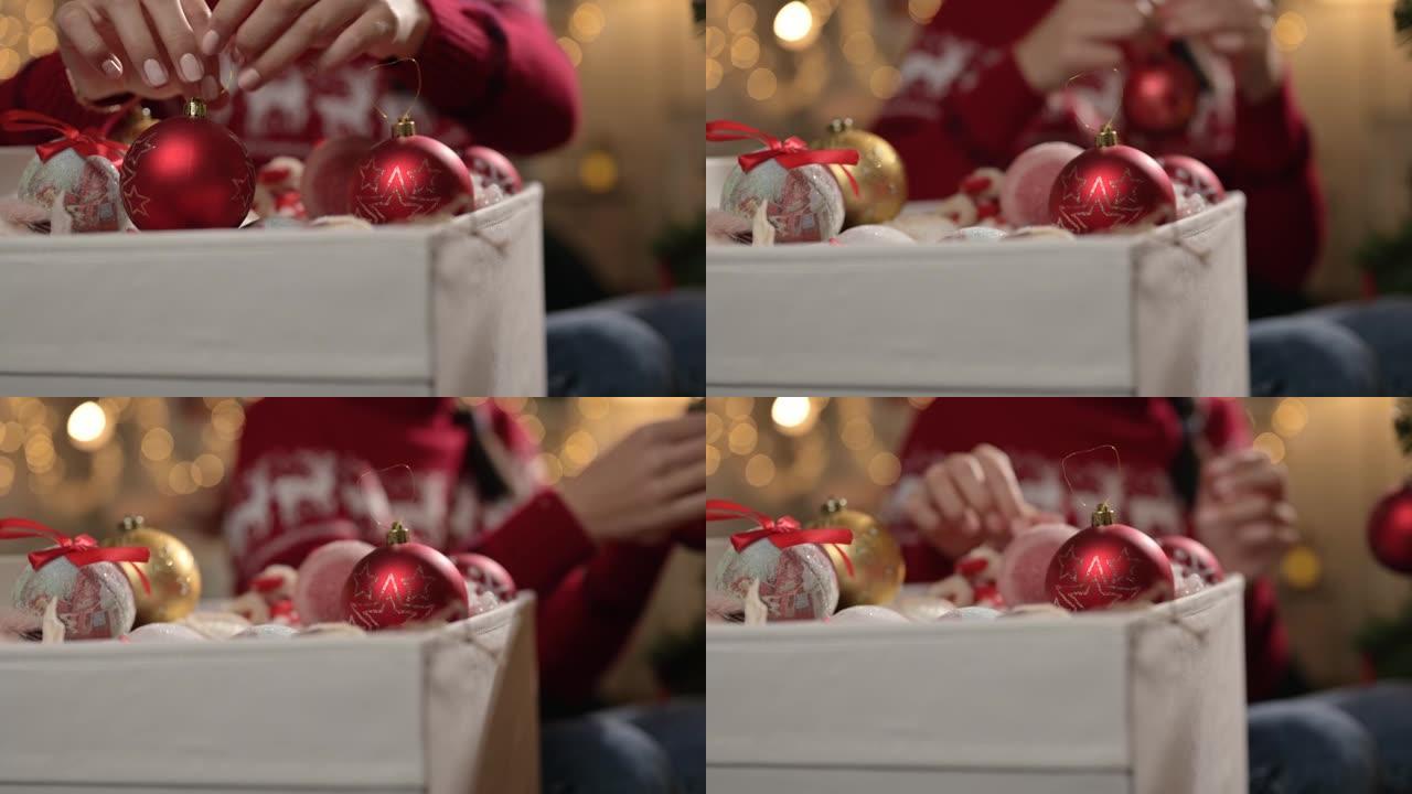 女性的手把圣诞玩具从盒子里拿出来。平安夜，装饰圣诞树概念。特写