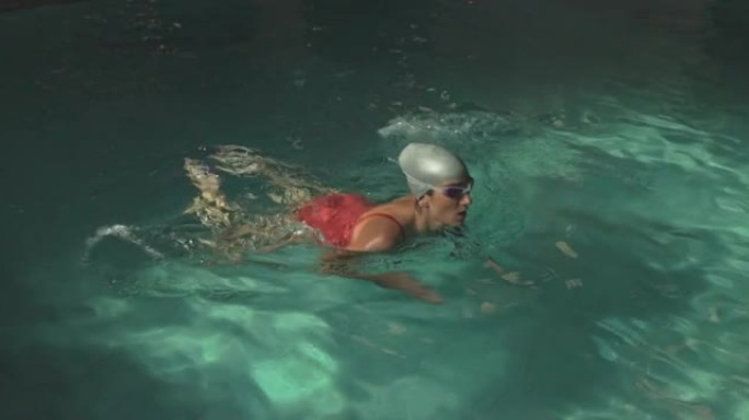 戴着泳帽和护目镜的年轻女子在酒店游泳池享受