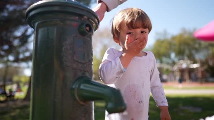 可爱的小孩在公园用干净的水龙头喝水