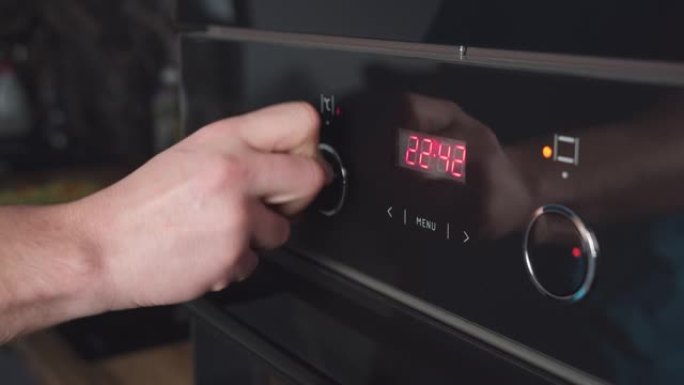 男人切换模式在烤箱面板上，男人的手打开烤箱开关，特写镜头。