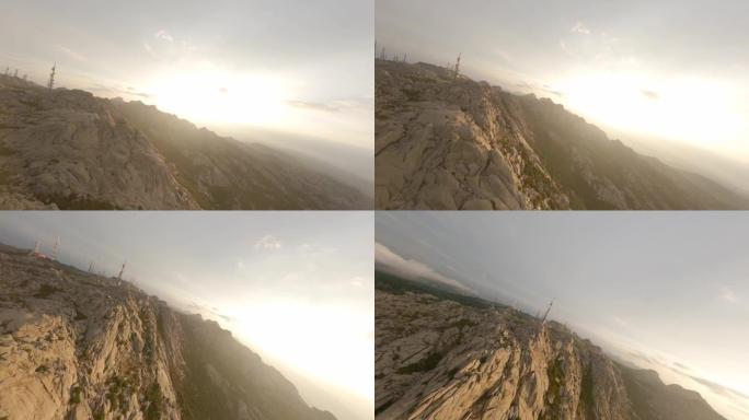FPV视频，山地冲浪，在美丽的日出期间，在带有花岗岩山脉和天线农场的云层中高速飞行。意大利撒丁岛的林