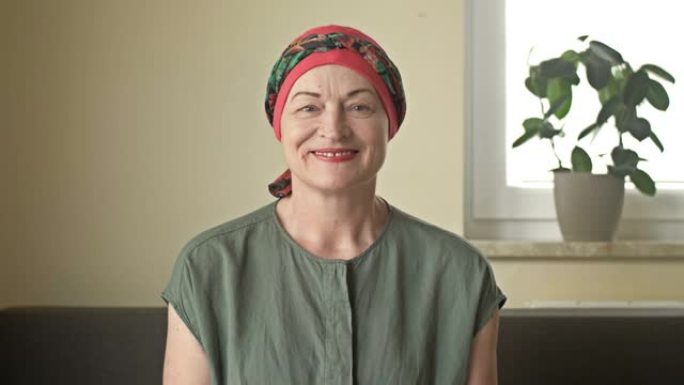 一个癌症女人的肖像。她从光头上取下围巾。化疗导致脱发。她的眼睛因痛苦，恐惧和绝望而流泪