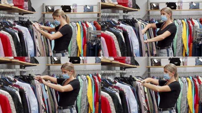 一个戴着医用口罩的女人正在一家小商店里挑选衣服。在各种各样的商品中寻找时尚的商品。去购物寻找折扣。