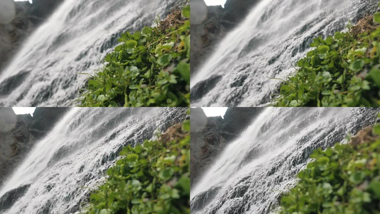 暴风雨的水流从高处坠落，山间瀑布和特写镜头周围的植被