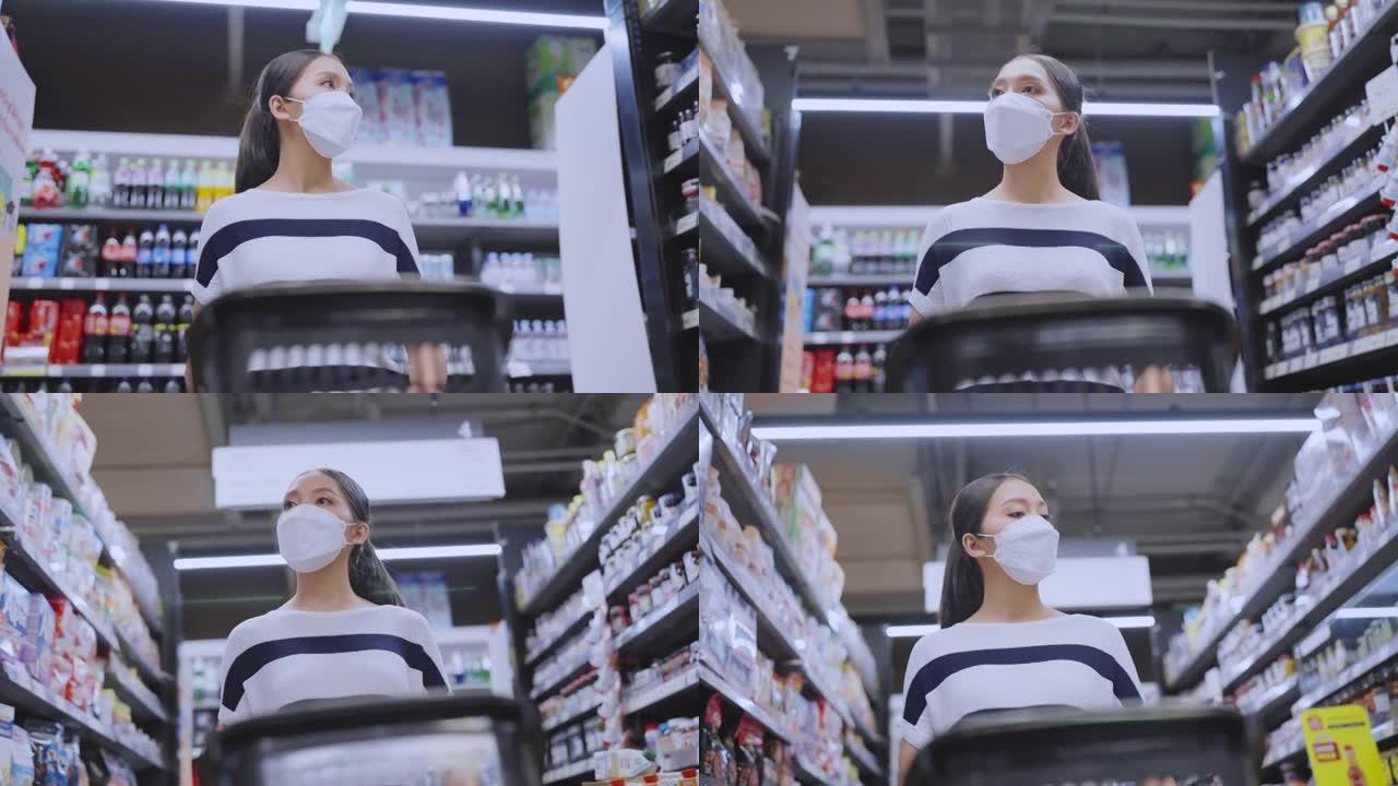 年轻的亚洲女性戴着保护性口罩手在杂货店百货商场选择新鲜产品或消费品，小心愉快的新的正常购物生活方式。