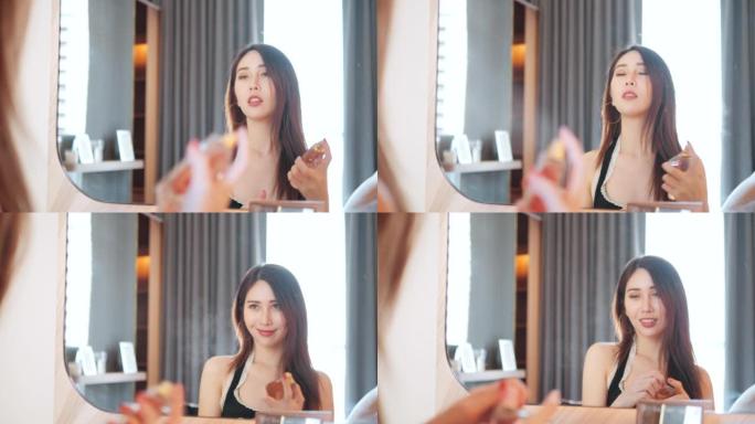 亚洲妇女在化妆镜前喷香水