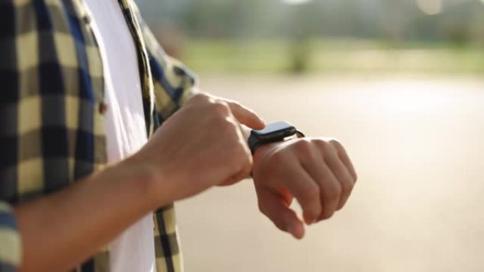男性在户外使用可穿戴智能手表的手的特写镜头。户外男人手上的智能手表。男人的手触摸智能手表。智能手表