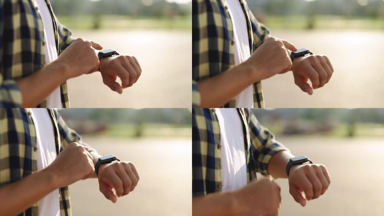 男性在户外使用可穿戴智能手表的手的特写镜头。户外男人手上的智能手表。男人的手触摸智能手表。智能手表